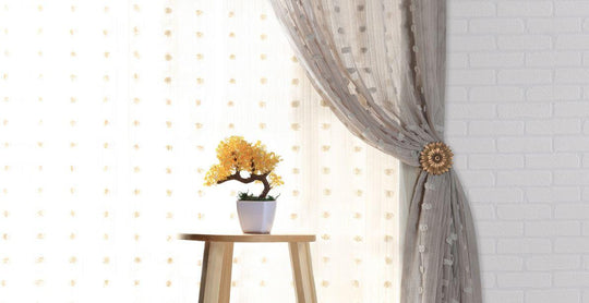 sheer grey curtains behind yellow bonsai tree